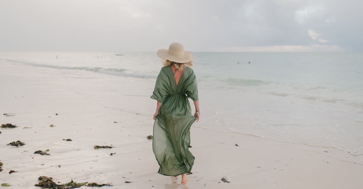 Malaysian tourist length of stay extension - Woman walking along wet sandy beach in windy day Malaysian tourist length of stay extension - Woman walking along wet sandy beach in windy day