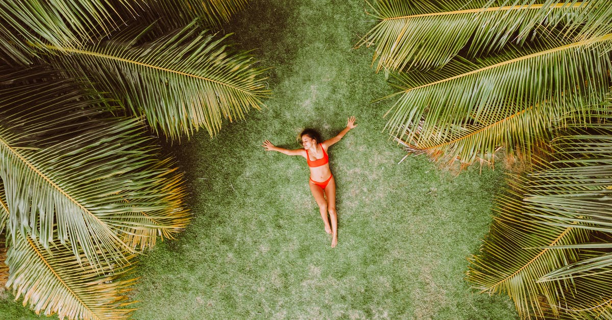 Malaysian tourist length of stay extension - Woman lying on green grass among palms at resort Malaysian tourist length of stay extension - Woman lying on green grass among palms at resort