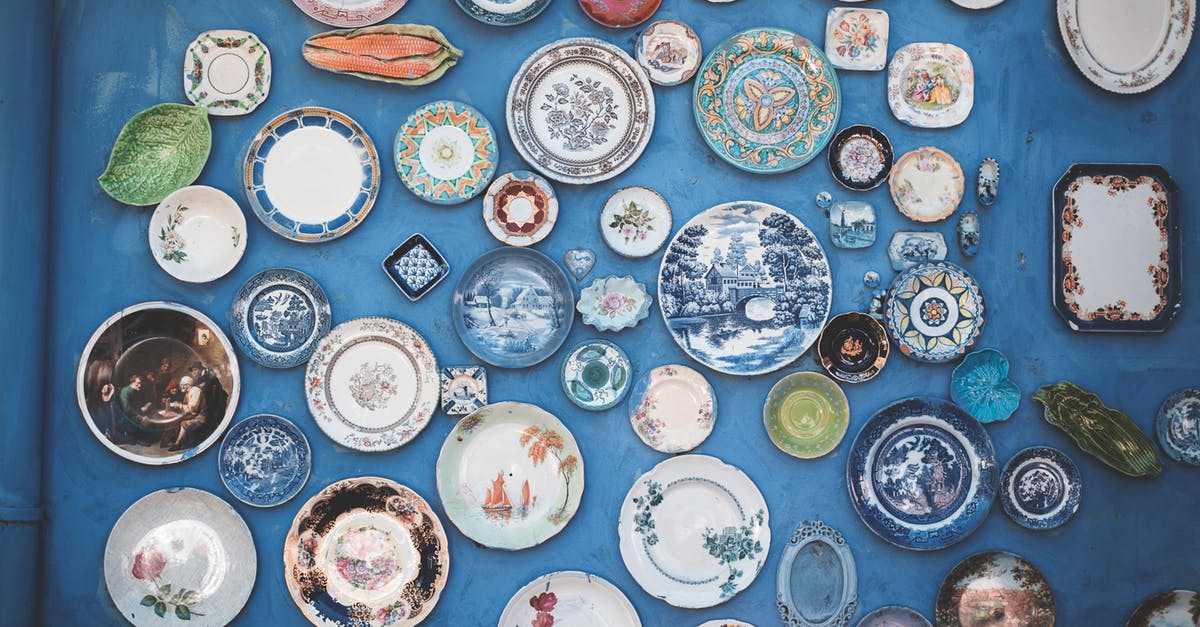 Managing frequent flyer miles when split across many different frequent-flyer programs - Composition of various decorative ornamental plates of different sizes and colors arranged on blue wall Managing frequent flyer miles when split across many different frequent-flyer programs - Composition of various decorative ornamental plates of different sizes and colors arranged on blue wall