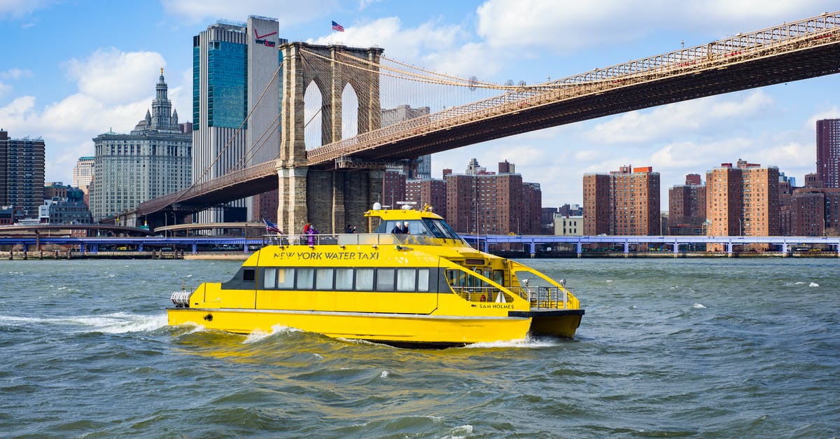 Manhattan Ferry/Water taxi to Brooklyn Bridge park - Yellow vessel boat sailing on river near bridge Manhattan Ferry/Water taxi to Brooklyn Bridge park - Yellow vessel boat sailing on river near bridge
