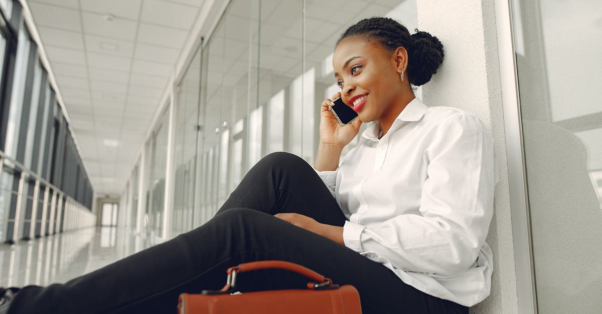 Maximum price for calling inside the EU, from when? - Smiling black woman talking on smartphone sitting on floor in corridor Maximum price for calling inside the EU, from when? - Smiling black woman talking on smartphone sitting on floor in corridor