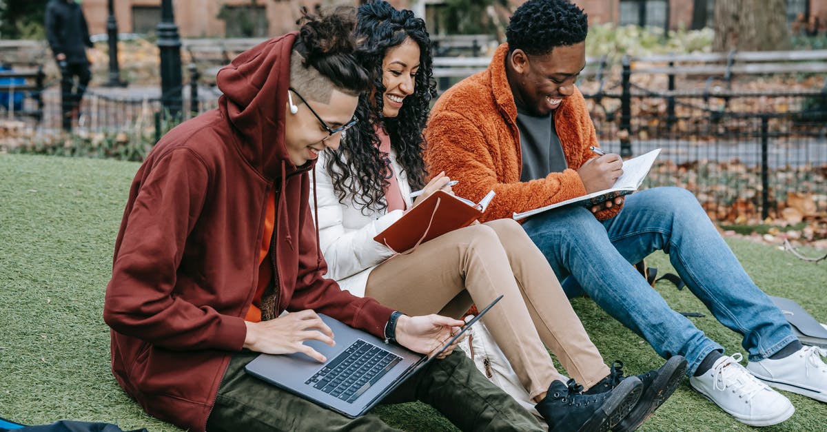 Meeting a friend at Heathrow - Happy multiracial group of students in casual clothes sitting together on grass and studying with laptop and books Meeting a friend at Heathrow - Happy multiracial group of students in casual clothes sitting together on grass and studying with laptop and books