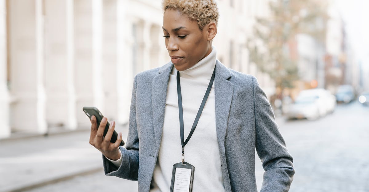 Mobile connectivity in Israel, in and outside small and large cities? - Confident young African American lady with badge around neck standing on pavement and watching video on smartphone in daylight Mobile connectivity in Israel, in and outside small and large cities? - Confident young African American lady with badge around neck standing on pavement and watching video on smartphone in daylight