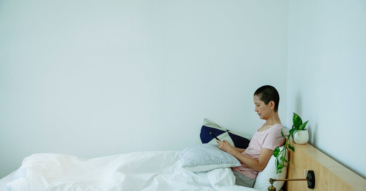 Mobile internet (3G) in UK for some days - Side view of concentrated lady in sleepwear browsing on cellphone while sitting in bed with pillows under blanket in light bedroom Mobile internet (3G) in UK for some days - Side view of concentrated lady in sleepwear browsing on cellphone while sitting in bed with pillows under blanket in light bedroom