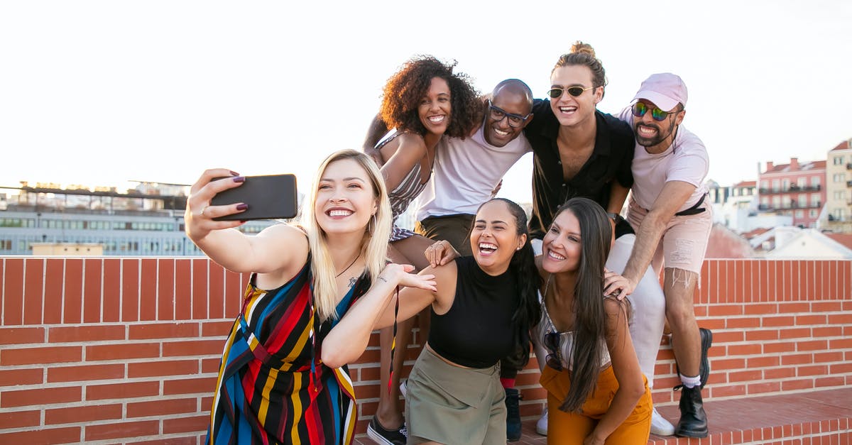 Mobile Roaming Charges in Europe - have they been abolished yet? - Group of cheerful young male and female multiracial friends laughing and taking selfie on smartphone while spending time together on terrace Mobile Roaming Charges in Europe - have they been abolished yet? - Group of cheerful young male and female multiracial friends laughing and taking selfie on smartphone while spending time together on terrace