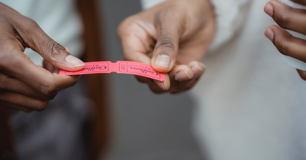 Modifying one leg of round trip ticket - Crop unrecognizable African American friends holding small paper tickets in hands on street in daytime Modifying one leg of round trip ticket - Crop unrecognizable African American friends holding small paper tickets in hands on street in daytime