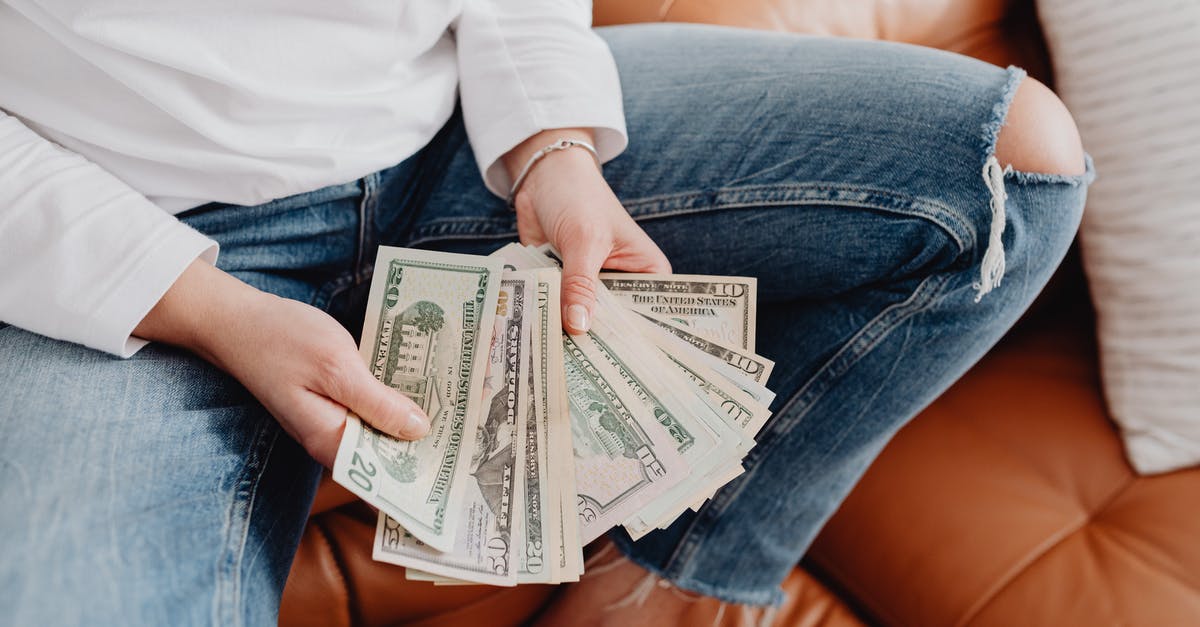 Money limit in the airport - Low Section of a Woman Sitting on a Leather Sofa and Showing Dollar Banknotes Money limit in the airport - Low Section of a Woman Sitting on a Leather Sofa and Showing Dollar Banknotes