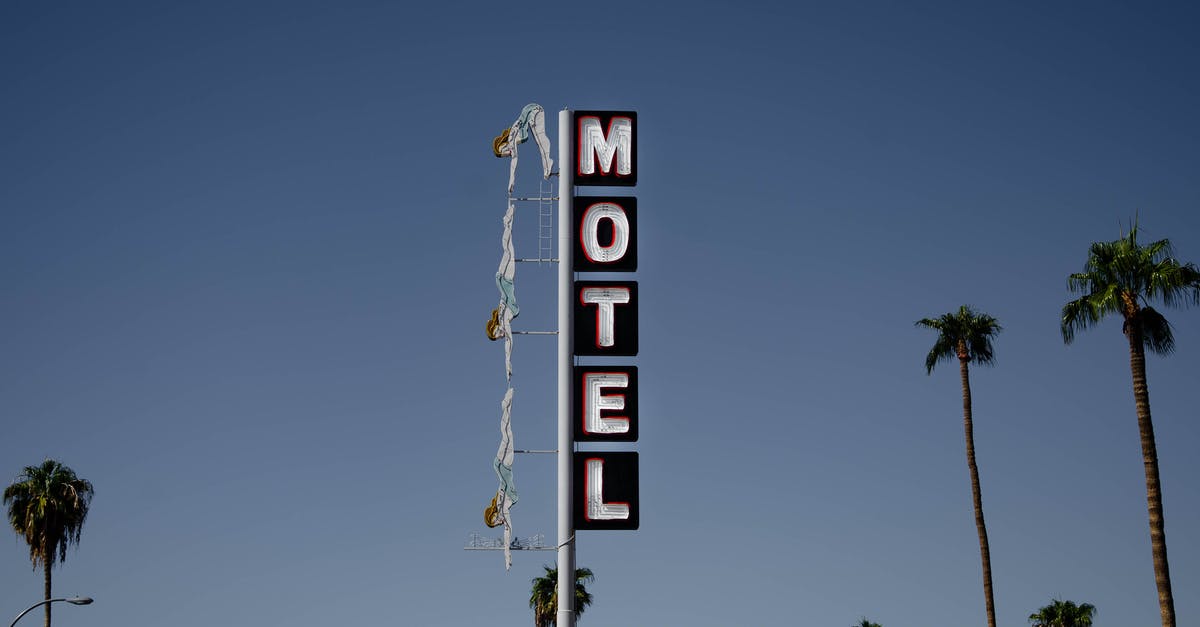 Motel on Route 66 in California, 1963 - Low angle of motel signboard on metal pillar located at roadside near tall palms against cloudless blue sky Motel on Route 66 in California, 1963 - Low angle of motel signboard on metal pillar located at roadside near tall palms against cloudless blue sky