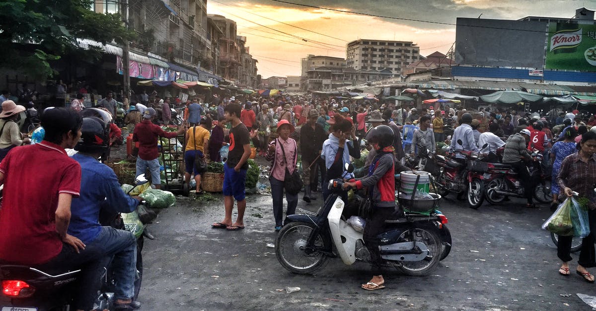 Motorcycle insurance in Southeast Asia - Woman in Gray and Red Jacket Riding White Motor in Crowded Place Motorcycle insurance in Southeast Asia - Woman in Gray and Red Jacket Riding White Motor in Crowded Place