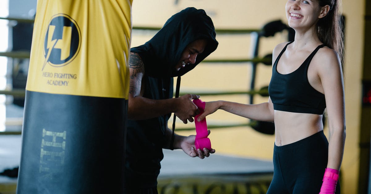 Must I pre-book bag wrap ar LHR? - Personal instructor wrapping pink boxing bandage on hand of smiling sportive female looking at camera during workout in gym with punching bag Must I pre-book bag wrap ar LHR? - Personal instructor wrapping pink boxing bandage on hand of smiling sportive female looking at camera during workout in gym with punching bag