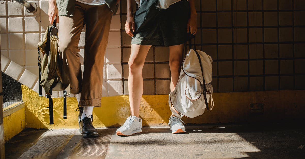 My girlfriend wants $1500 to prove she can look after herself when she arrives in Australia [duplicate] - Lower body parts of crop anonymous stylish couple leaning on tiled wall in pedestrian passage