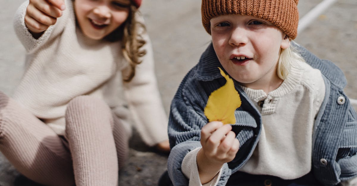 My sister will sponsor her place for my stay in UK,what should my sister show of proof for my UK Visa? - Adorable little boy in hat with yellow withered leaf looking at camera while sitting on sidewalk with cute girl on blurred background