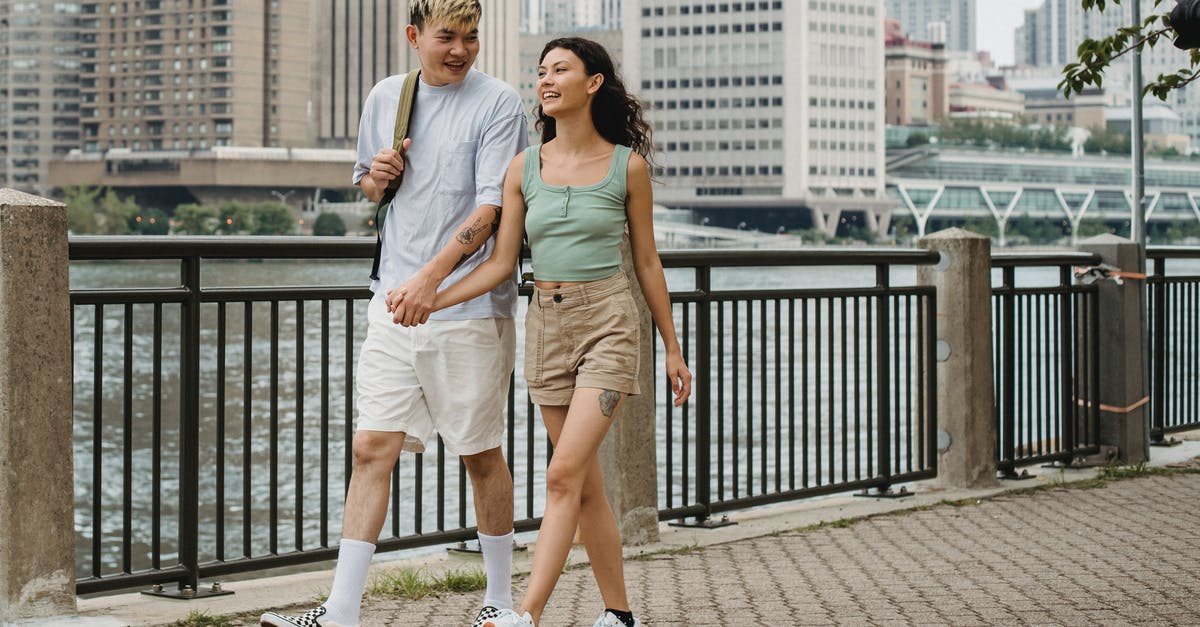 My UK Visa has been issued with a date of expiry that is earlier than my dates of travel. How can I fix it? [closed] - Happy smiling multiracial couple holding hands and walking on embankment