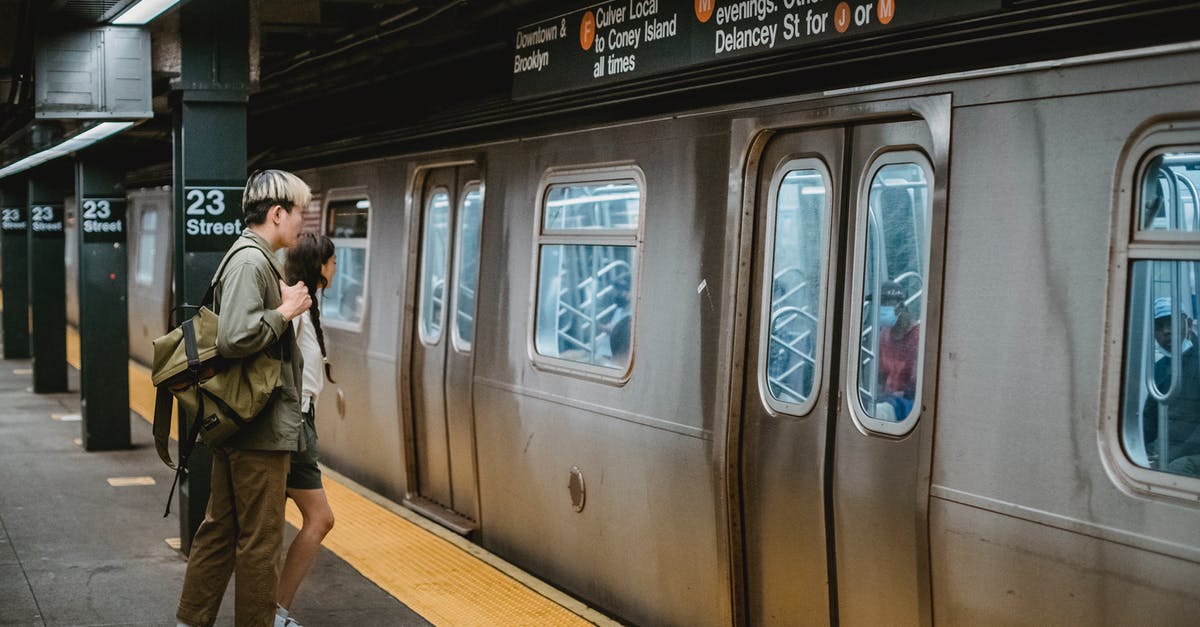 Newark transit from terminal B to terminal A on separate itineraries - Young couple standing in front of train on metro station platform Newark transit from terminal B to terminal A on separate itineraries - Young couple standing in front of train on metro station platform
