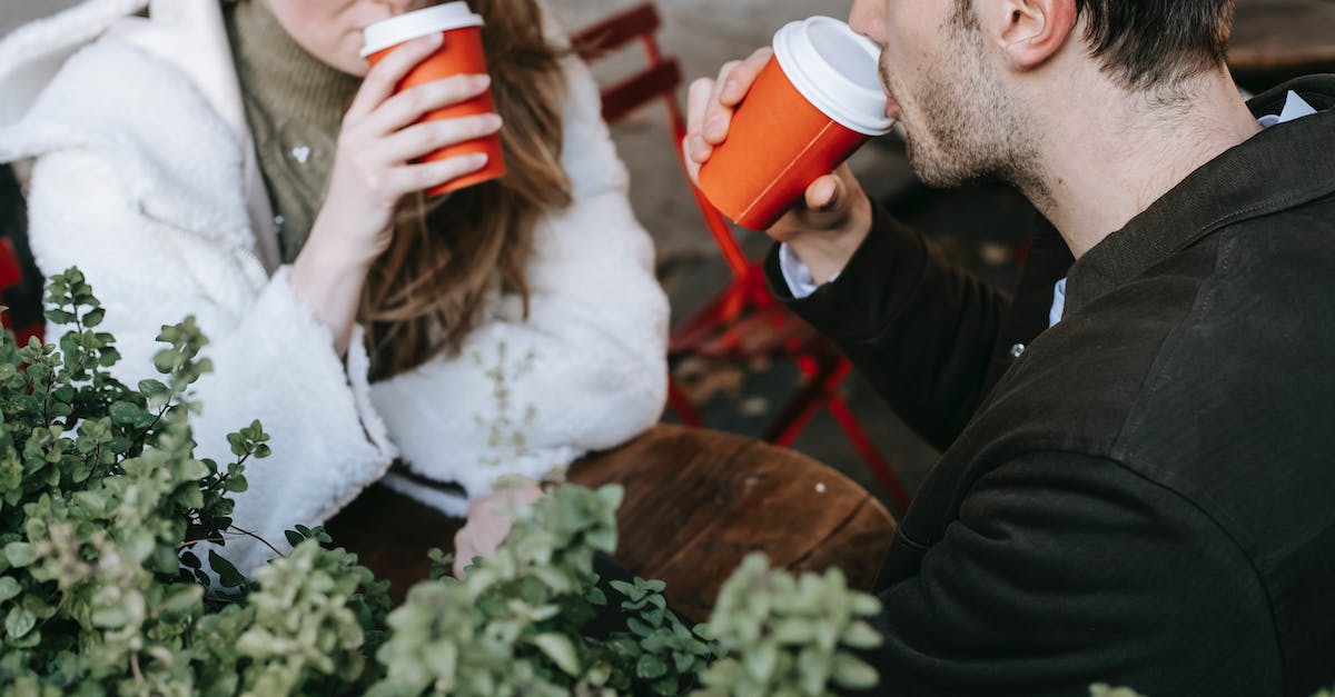 Newbie snowboarding options a couple of days not too far from Stockholm - Crop man and woman drinking coffee to go in street cafeteria