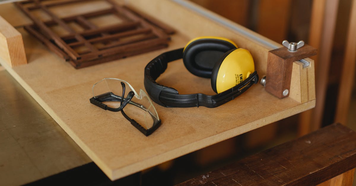 Noise cancelling headphones you can turn the noise cancellation on/off in [closed] - From above of noise cancelling headphones with protective glasses for joinery on wooden table in workroom