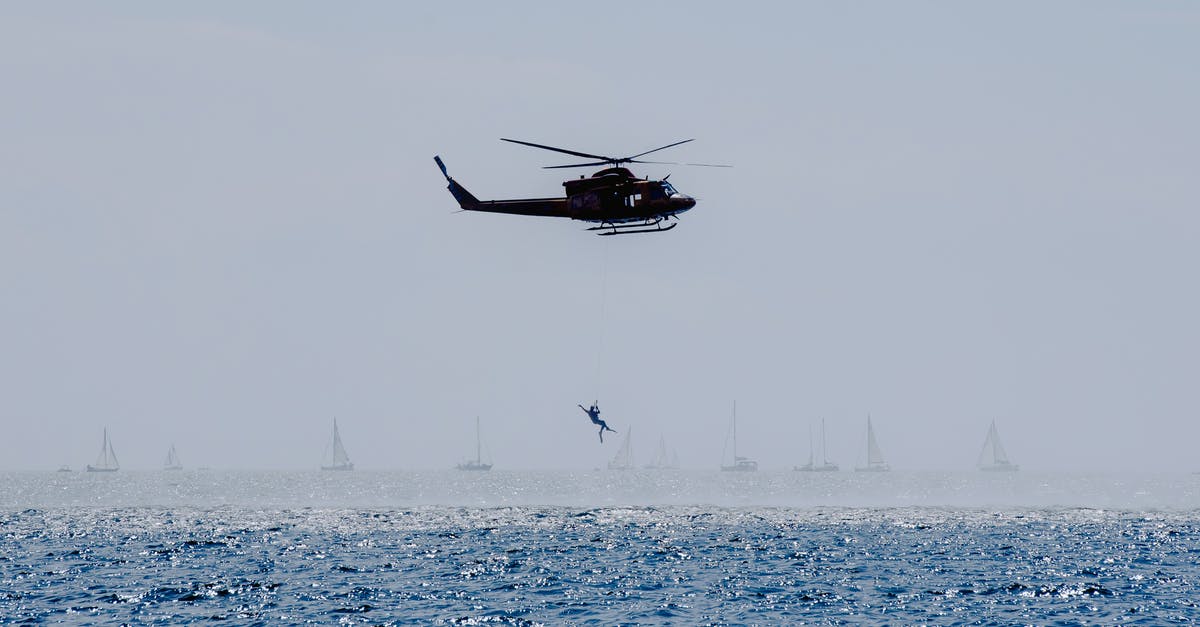 Normandy, France: Where to see the WW2 landing craft? - Copter landing anonymous military parachutist over wavy ocean with sailboats during professional practice in daytime Normandy, France: Where to see the WW2 landing craft? - Copter landing anonymous military parachutist over wavy ocean with sailboats during professional practice in daytime