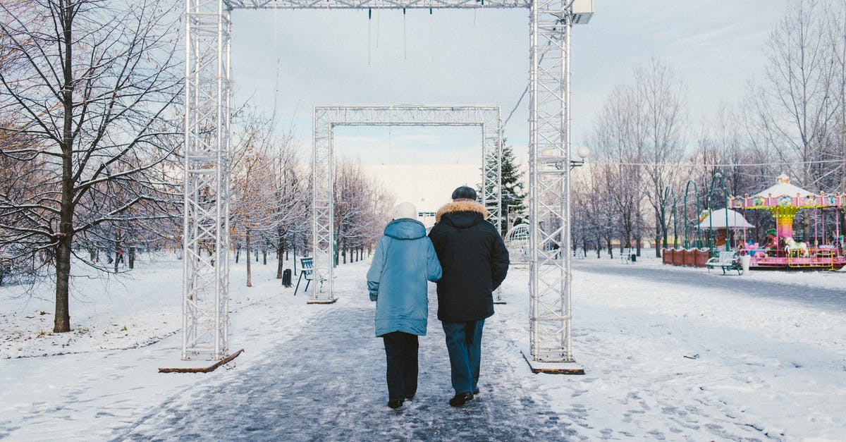 North Korean themed theme parks - Back view of anonymous couple strolling on snowy walkway with rectangular shaped arches in amusement park in town North Korean themed theme parks - Back view of anonymous couple strolling on snowy walkway with rectangular shaped arches in amusement park in town