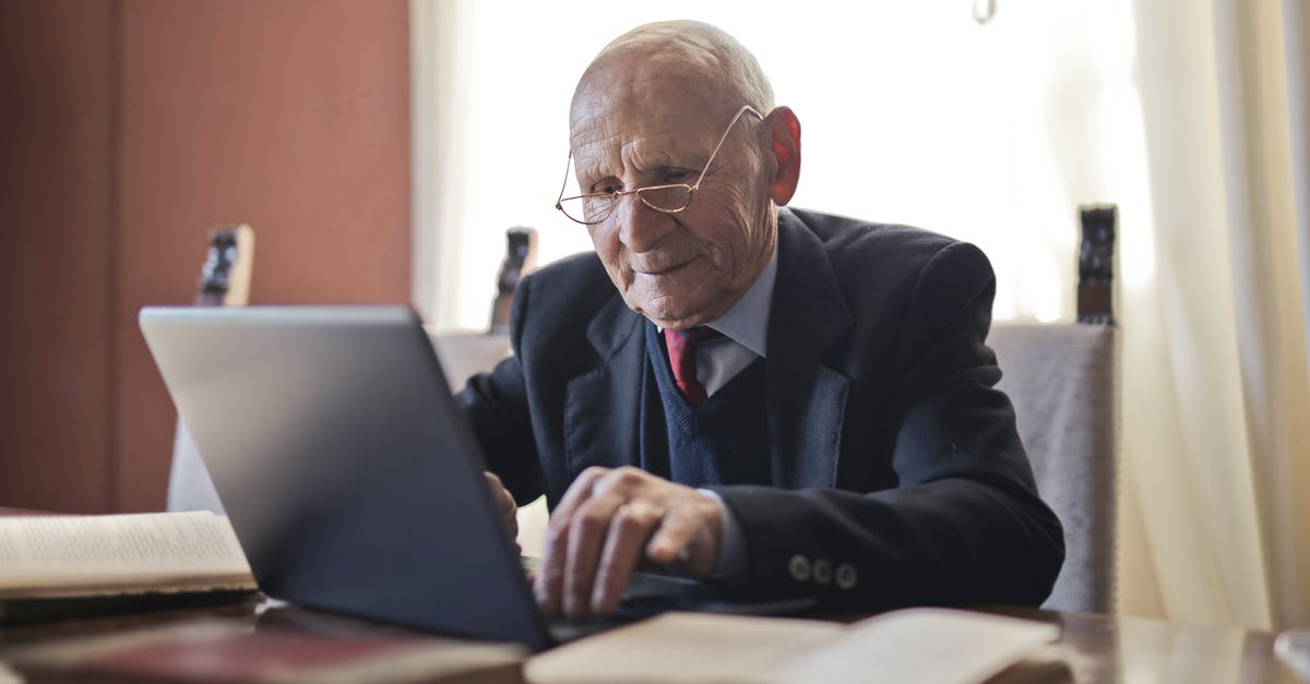 Not able to manage award flight via Manage bookings - Focused elderly man in formal black suit and eyeglasses using laptop while sitting at wooden table with books in light room Not able to manage award flight via Manage bookings - Focused elderly man in formal black suit and eyeglasses using laptop while sitting at wooden table with books in light room