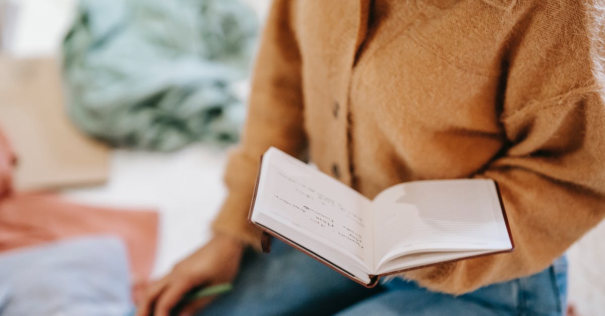 Not able to read bus schedule in France - Crop anonymous female in casual clothes reading notes in notebook while sitting on floor in light room Not able to read bus schedule in France - Crop anonymous female in casual clothes reading notes in notebook while sitting on floor in light room
