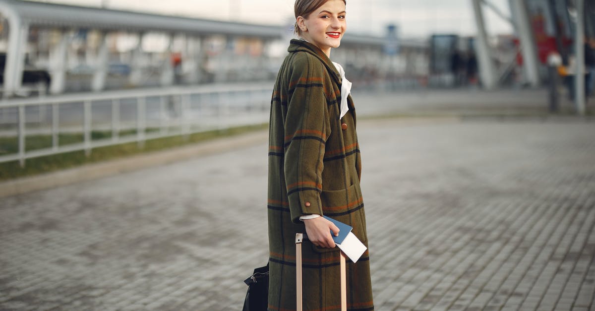 Not getting passport stamped when entering USA from abroad - Side view of positive young woman in warm clothes smiling at camera while carrying luggage with passport walking along airport terminal Not getting passport stamped when entering USA from abroad - Side view of positive young woman in warm clothes smiling at camera while carrying luggage with passport walking along airport terminal