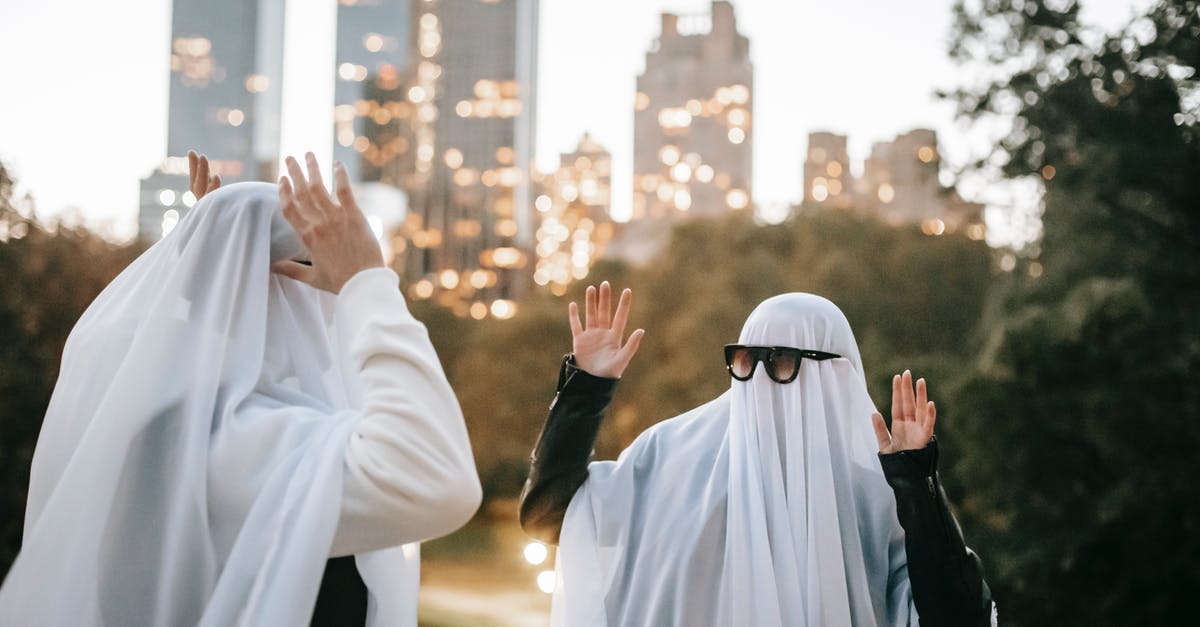 Odd, funky festivals in the Northeast of the US? - Funny unrecognizable couple with raised arms wearing ghost costumes and sunglasses looking at each other while standing in park with glowing skyscrapers on blurred background during Halloween Odd, funky festivals in the Northeast of the US? - Funny unrecognizable couple with raised arms wearing ghost costumes and sunglasses looking at each other while standing in park with glowing skyscrapers on blurred background during Halloween