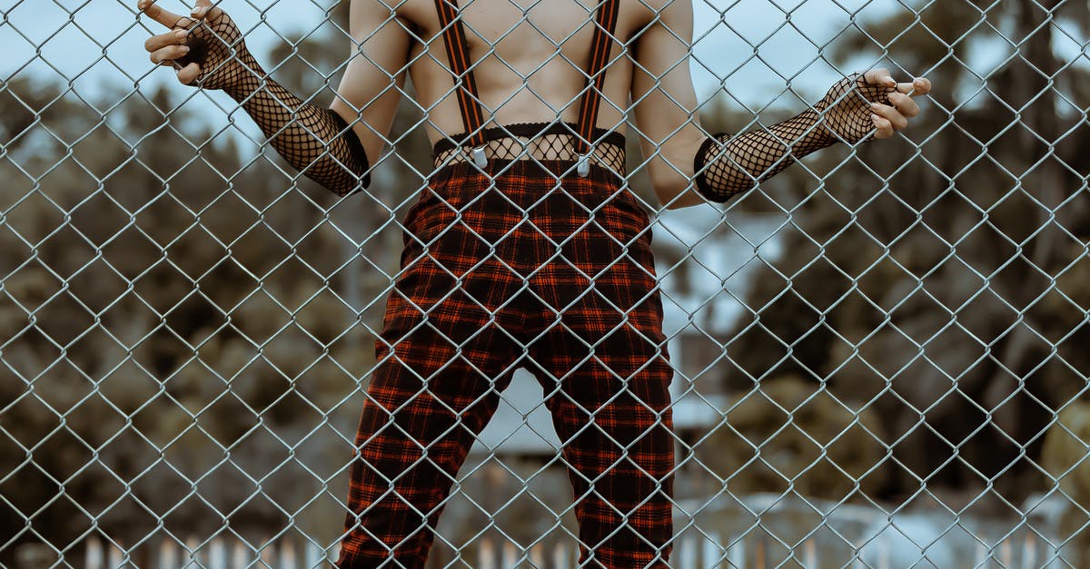 Odd, funky festivals in the Northeast of the US? - Crop faceless shirtless man in checkered trousers behind net fence Odd, funky festivals in the Northeast of the US? - Crop faceless shirtless man in checkered trousers behind net fence