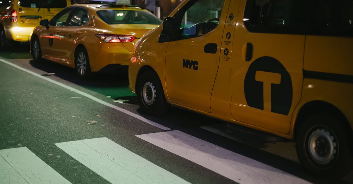 One way car hire US - Modern various yellow taxi cars parked on street at night in New York City One way car hire US - Modern various yellow taxi cars parked on street at night in New York City