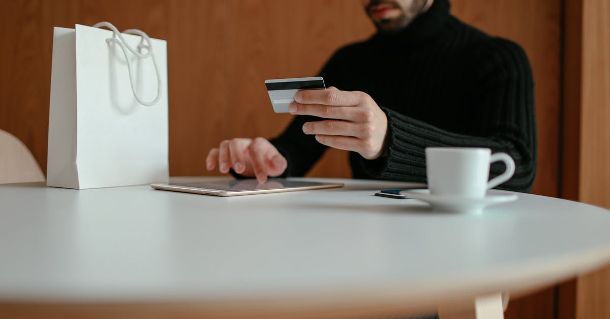 Online Bank Statements Accepted for Japan visa? - Crop focused bearded young man using tablet while doing online purchase with credit card sitting at table in modern cafe with coffee cup and shopping bag Online Bank Statements Accepted for Japan visa? - Crop focused bearded young man using tablet while doing online purchase with credit card sitting at table in modern cafe with coffee cup and shopping bag