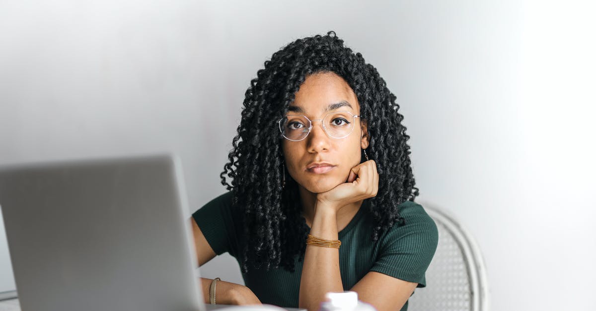 Online check in for connecting flight (different airlines) - Serious ethnic young woman using laptop at home Online check in for connecting flight (different airlines) - Serious ethnic young woman using laptop at home