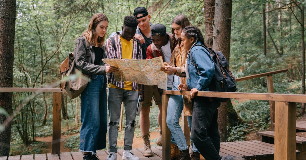 Online hiking map for Alps - People Standing on a Wooden Bridge while Reading a Map Online hiking map for Alps - People Standing on a Wooden Bridge while Reading a Map