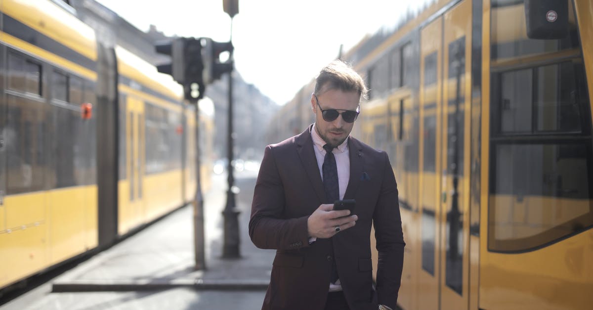 Online resource for finding co-working space while traveling - Brutal male entrepreneur in elegant suit and sunglasses standing with hand in pocket on street between trams and messaging on cellphone Online resource for finding co-working space while traveling - Brutal male entrepreneur in elegant suit and sunglasses standing with hand in pocket on street between trams and messaging on cellphone