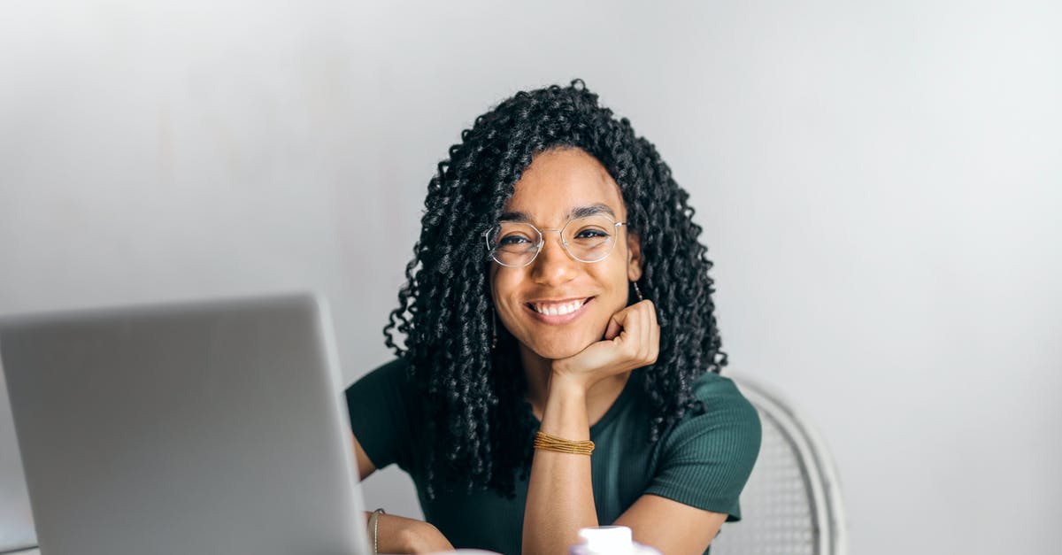 Online resource for finding co-working space while traveling - Happy ethnic woman sitting at table with laptop Online resource for finding co-working space while traveling - Happy ethnic woman sitting at table with laptop
