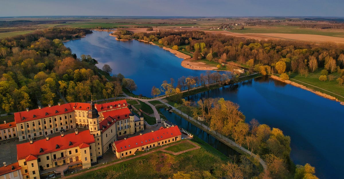 Options to travel from Moscow to Belarus and the EU on a foreign passport - Old castle on river shore in valley on autumn day Options to travel from Moscow to Belarus and the EU on a foreign passport - Old castle on river shore in valley on autumn day