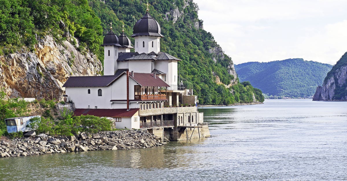 Overstay in Serbia - White and Black House Located at Riverside on Mountain Slope at Daytime Overstay in Serbia - White and Black House Located at Riverside on Mountain Slope at Daytime