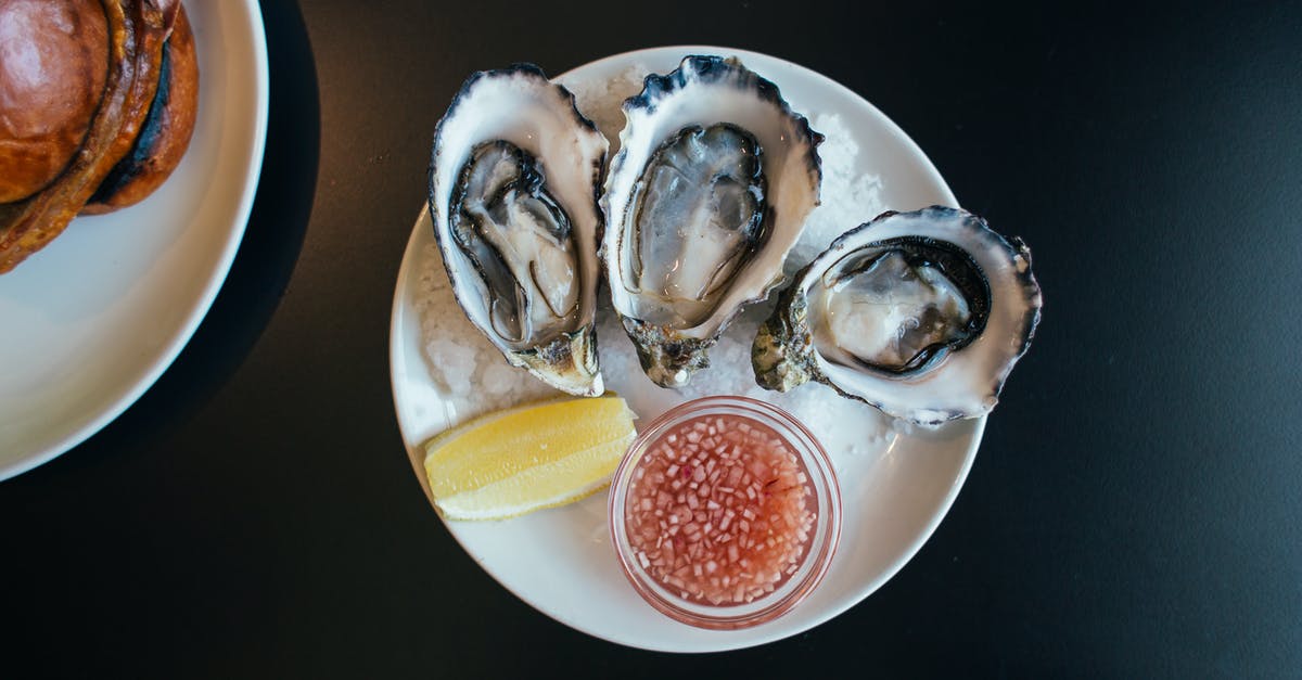 Oyster card—London only? - Top view of sophisticated seafood dish with oysters served on plate with sauce and lemon on table in modern restaurant Oyster card—London only? - Top view of sophisticated seafood dish with oysters served on plate with sauce and lemon on table in modern restaurant