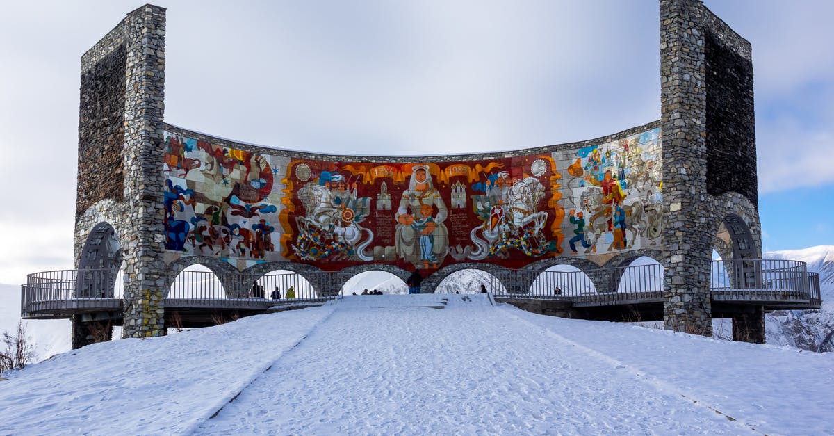 Painting location identification - Low angle of old stone arched Russia Georgia Friendship Monument with tile mural inside located on snowy hill in Gudauri Painting location identification - Low angle of old stone arched Russia Georgia Friendship Monument with tile mural inside located on snowy hill in Gudauri