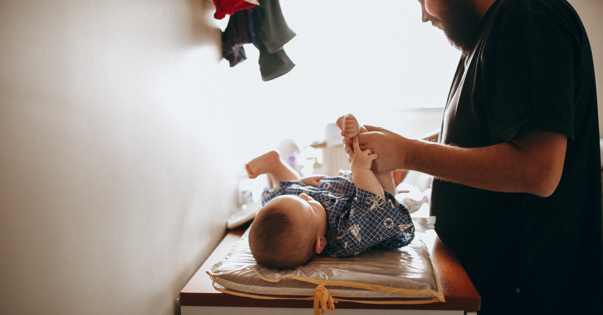 Parents name change UK standard visitor visa - Young father changing diaper of newborn baby Parents name change UK standard visitor visa - Young father changing diaper of newborn baby