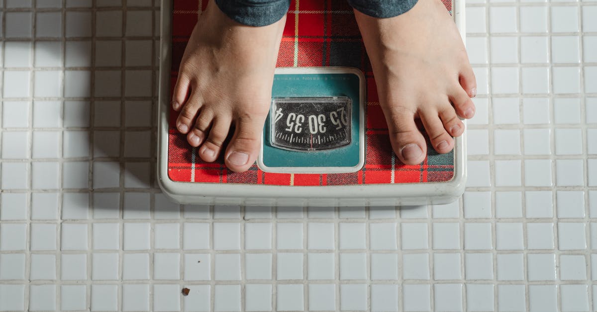 Passport control going from London to Brussels or Amsterdam - From above crop anonymous barefoot child in jeans standing on weigh scales on tiled floor of bathroom Passport control going from London to Brussels or Amsterdam - From above crop anonymous barefoot child in jeans standing on weigh scales on tiled floor of bathroom