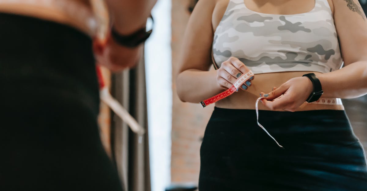 Passport control going from London to Brussels or Amsterdam - Woman measuring waist with tape in gym Passport control going from London to Brussels or Amsterdam - Woman measuring waist with tape in gym
