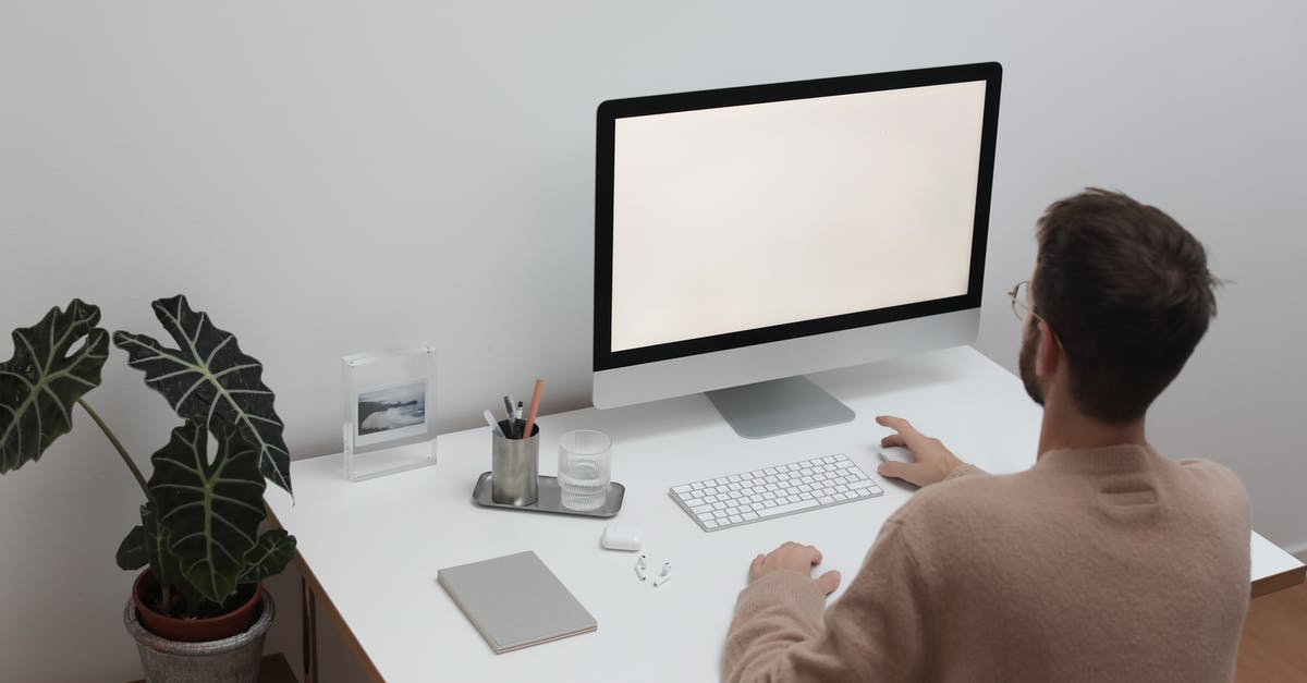 Personal Visit on Business Visa Type C - Back view of anonymous male in sweater sitting at table with notepad and earbuds while browsing computer