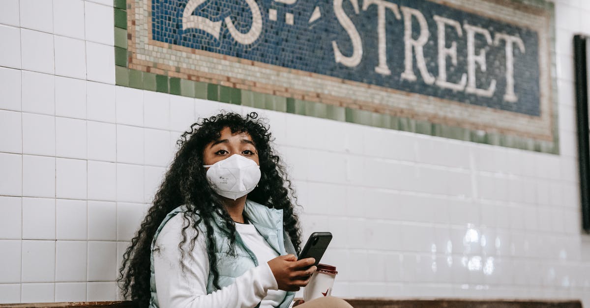 Phone dying when using mobile myTix NJ Transit app - what can be done to protect? - Emotionless African American female in casual wear and protective mask using mobile phone and looking away while sitting on bench in metro station platform in New York Phone dying when using mobile myTix NJ Transit app - what can be done to protect? - Emotionless African American female in casual wear and protective mask using mobile phone and looking away while sitting on bench in metro station platform in New York