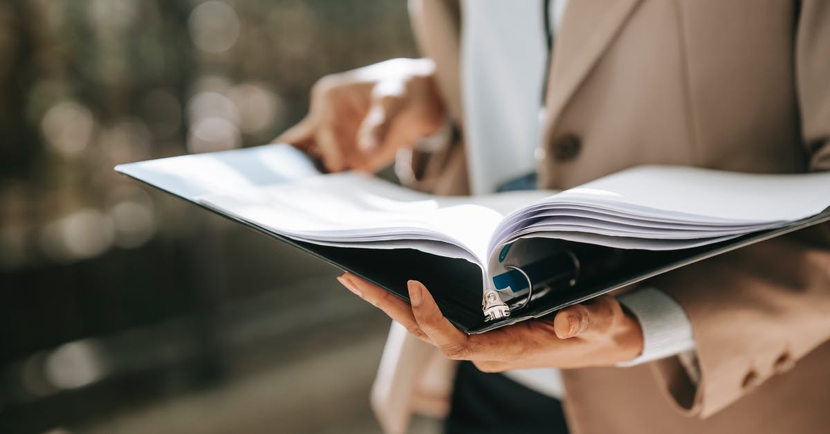 Photocopies of important documents stolen - Crop faceless female entrepreneur in formal jacket turning pages of documents in folder while reading Photocopies of important documents stolen - Crop faceless female entrepreneur in formal jacket turning pages of documents in folder while reading
