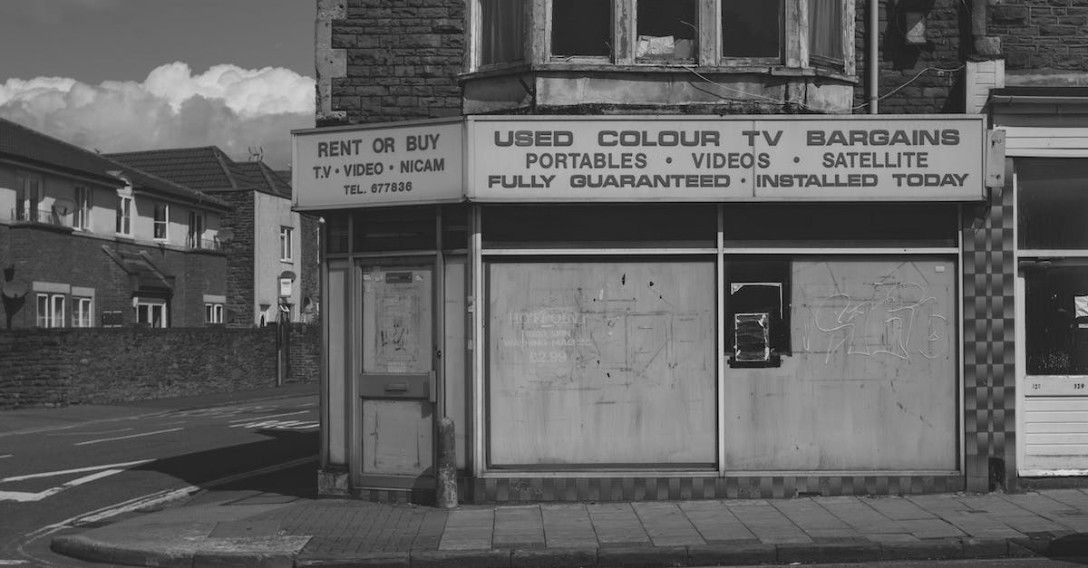 Planning to buy a TV in Dubai to bring to India, what issues may I encounter? [closed] - Black and white of old abandoned building with vintage shop of used electronic goods on empty street of city