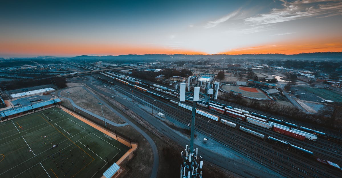 Portugal to USA by cargo ship? - Aerial view of industrial district of Chattanooga city with green rugby fields and modern cell tower located near railroad tracks against sunset sky Portugal to USA by cargo ship? - Aerial view of industrial district of Chattanooga city with green rugby fields and modern cell tower located near railroad tracks against sunset sky