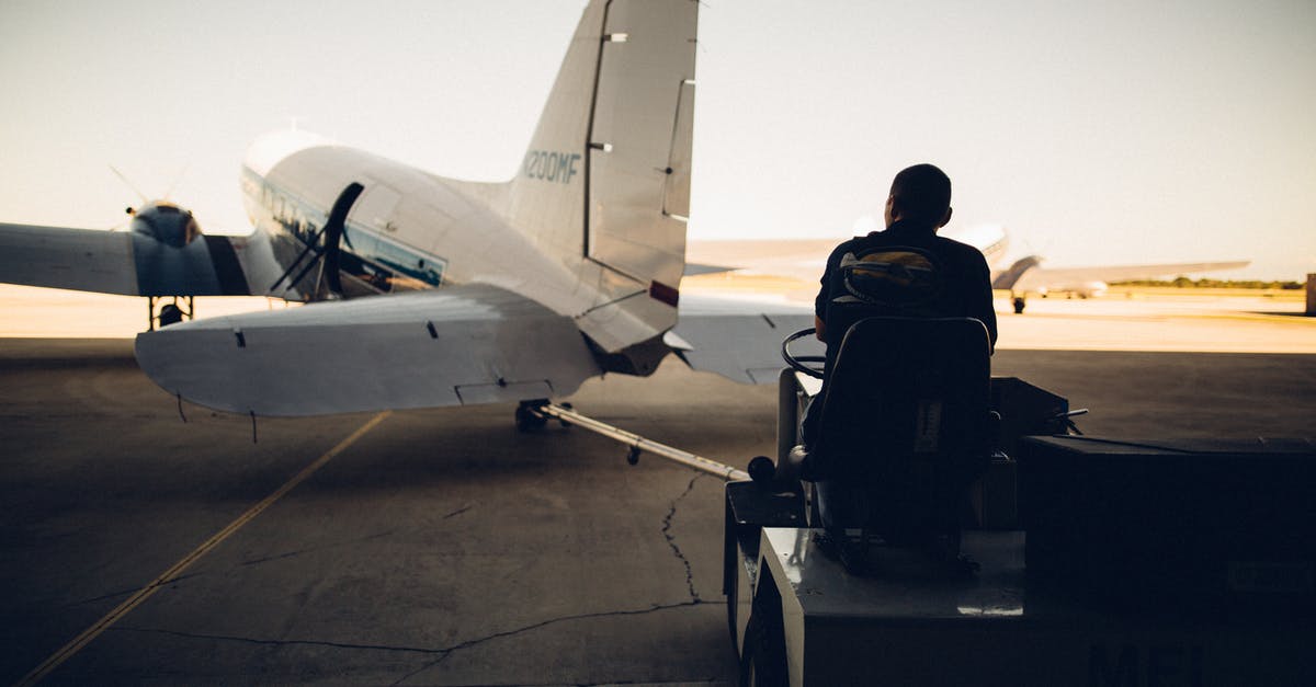 Possibility of delayed luggage during transfer at DXB - Silhouette of worker driving baggage carrier on paved airfield with airplane before flight Possibility of delayed luggage during transfer at DXB - Silhouette of worker driving baggage carrier on paved airfield with airplane before flight