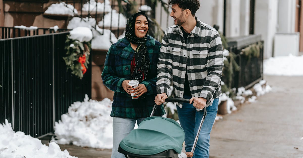 Possibility of getting my schengen visa revoked if other family members not going? - Happy ethnic couple walking with stroller on street in residential city district Possibility of getting my schengen visa revoked if other family members not going? - Happy ethnic couple walking with stroller on street in residential city district
