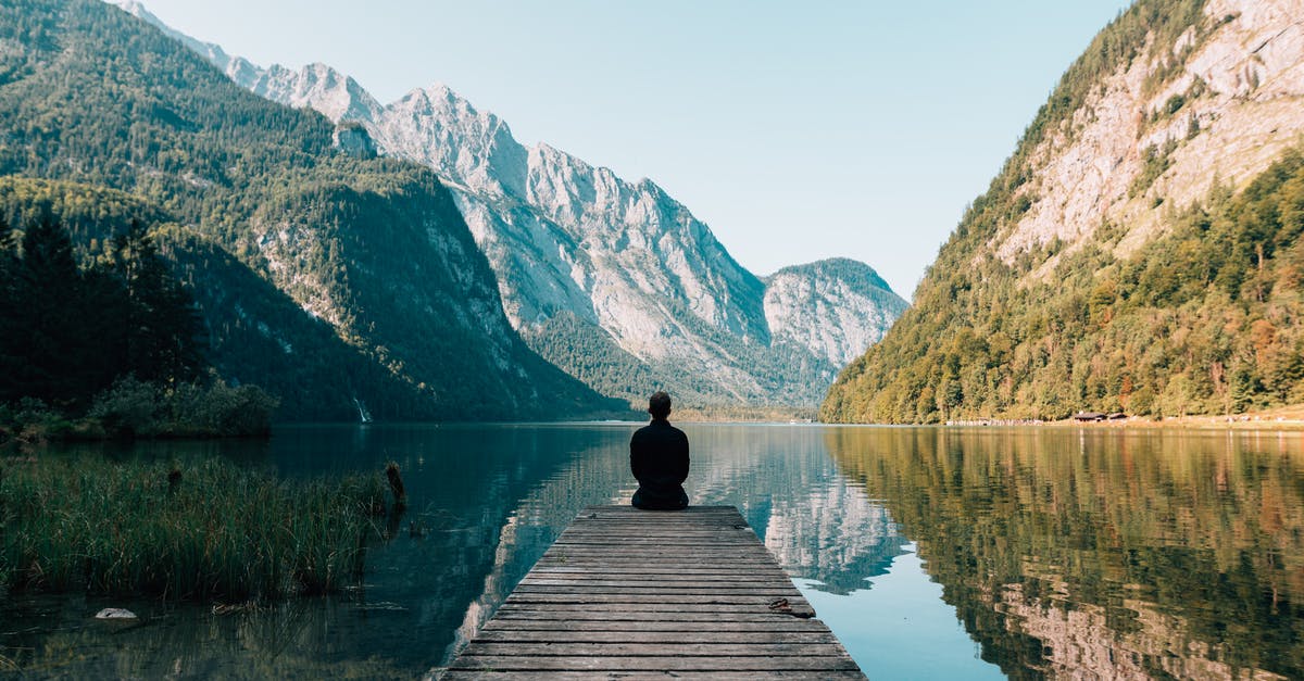 Possible to Travel to A Quiet Place? - A Person Sitting on Wooden Planks Across the Lake Scenery Possible to Travel to A Quiet Place? - A Person Sitting on Wooden Planks Across the Lake Scenery
