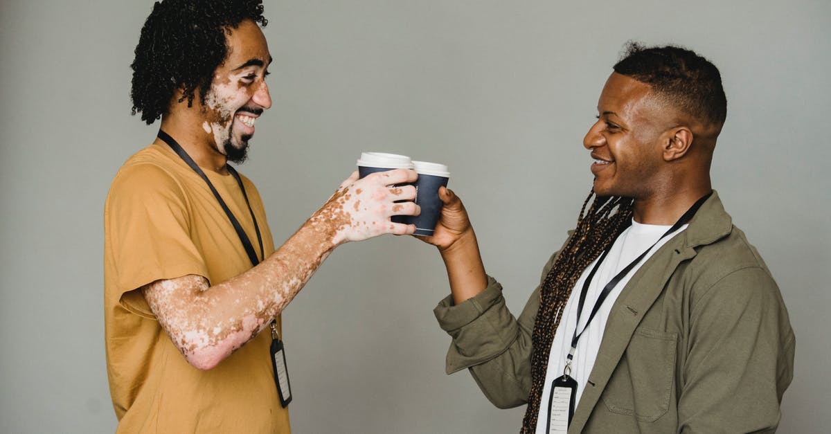 Prevalence of ATMs that accept JCB cards - Side view of cheerful androgynous man with Afro braids standing on gray background near black coworker with vitiligo skin during coffee break Prevalence of ATMs that accept JCB cards - Side view of cheerful androgynous man with Afro braids standing on gray background near black coworker with vitiligo skin during coffee break