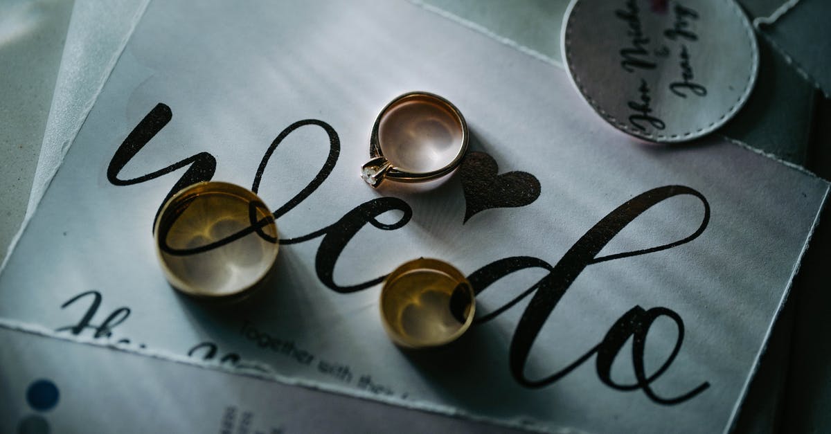 Procedure for Schengen visa invitation letter and documents from EU nationals - From above of expensive golden rings placed on piece of paper with inscription on table in daylight in room inside